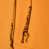 Close-up of orange fabric with braided drawstrings on a matching background