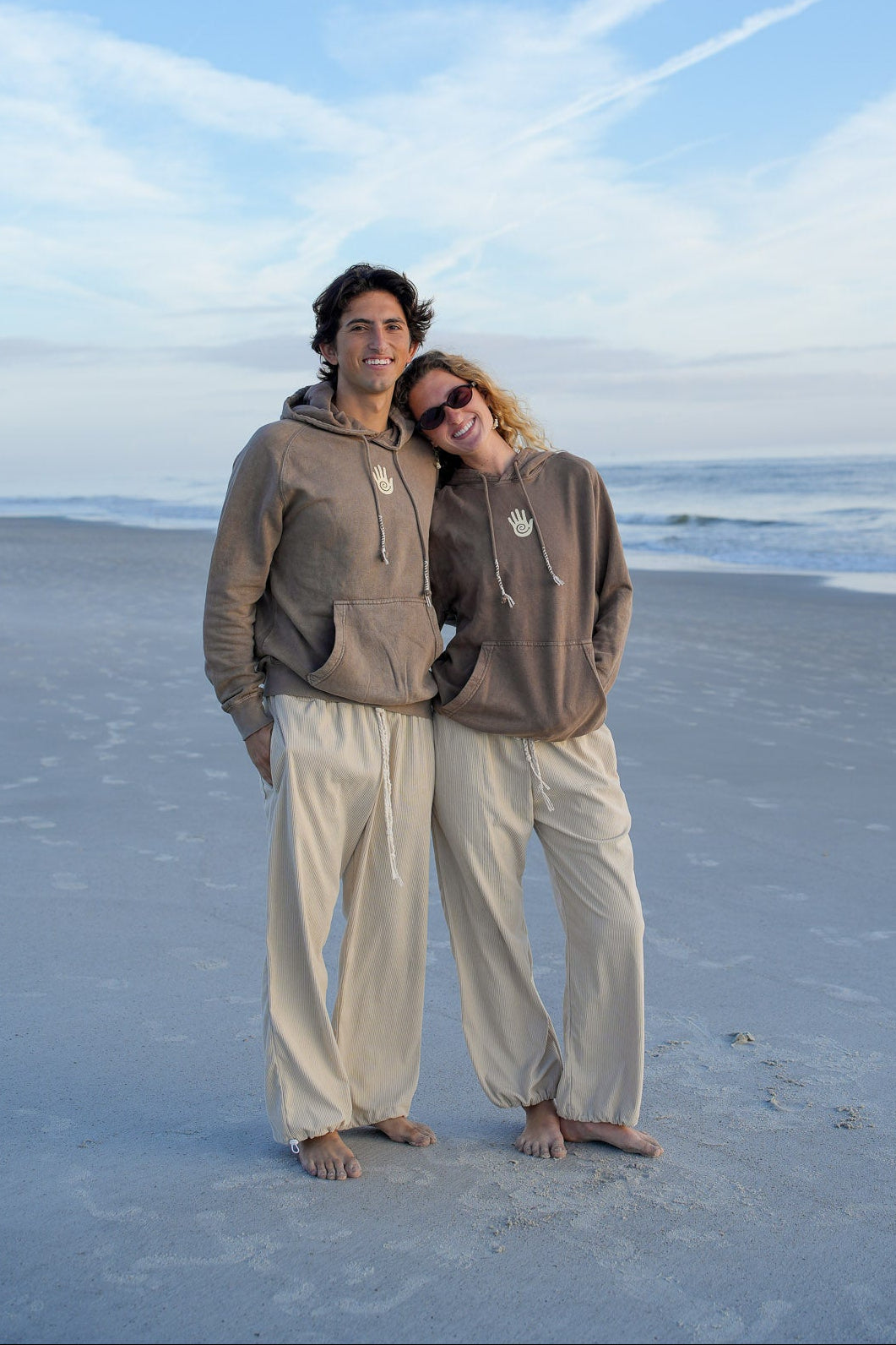 Two people standing on a sandy beach with a clear blue sky.