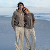 Two people standing on a sandy beach with a clear blue sky.