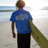 Person holding a surfboard on a beach with a blue sky and ocean in the background