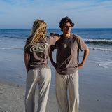 Two people standing on a beach with ocean waves in the background