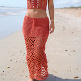 Woman wearing a red crochet outfit on a beach