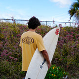 Person holding a surfboard with a spiral design on a beach