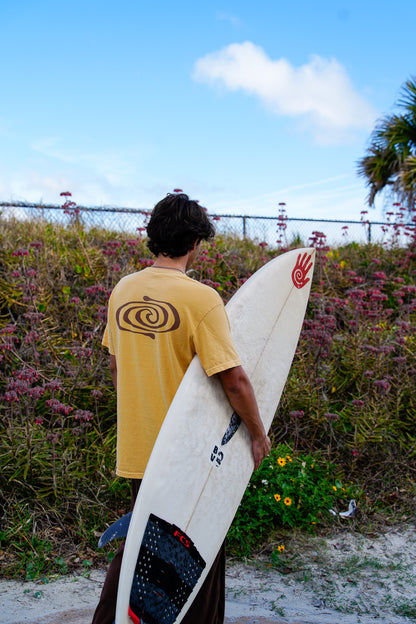Person holding a surfboard with a spiral design on a beach