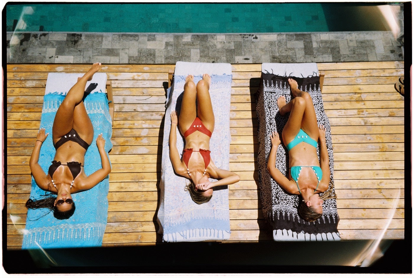 Three friends in SOHO bikinis lying poolside, shot on Kodak film
